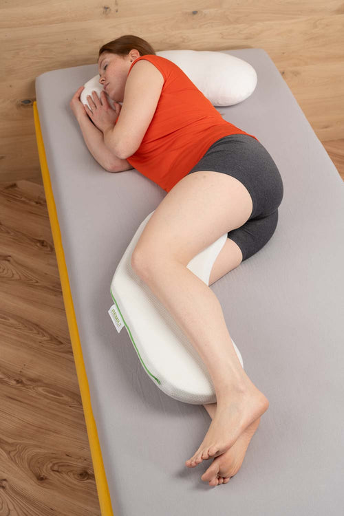Frau liegt seitlich auf einem ergonomischen Kissen zur ruhigen Lagerung