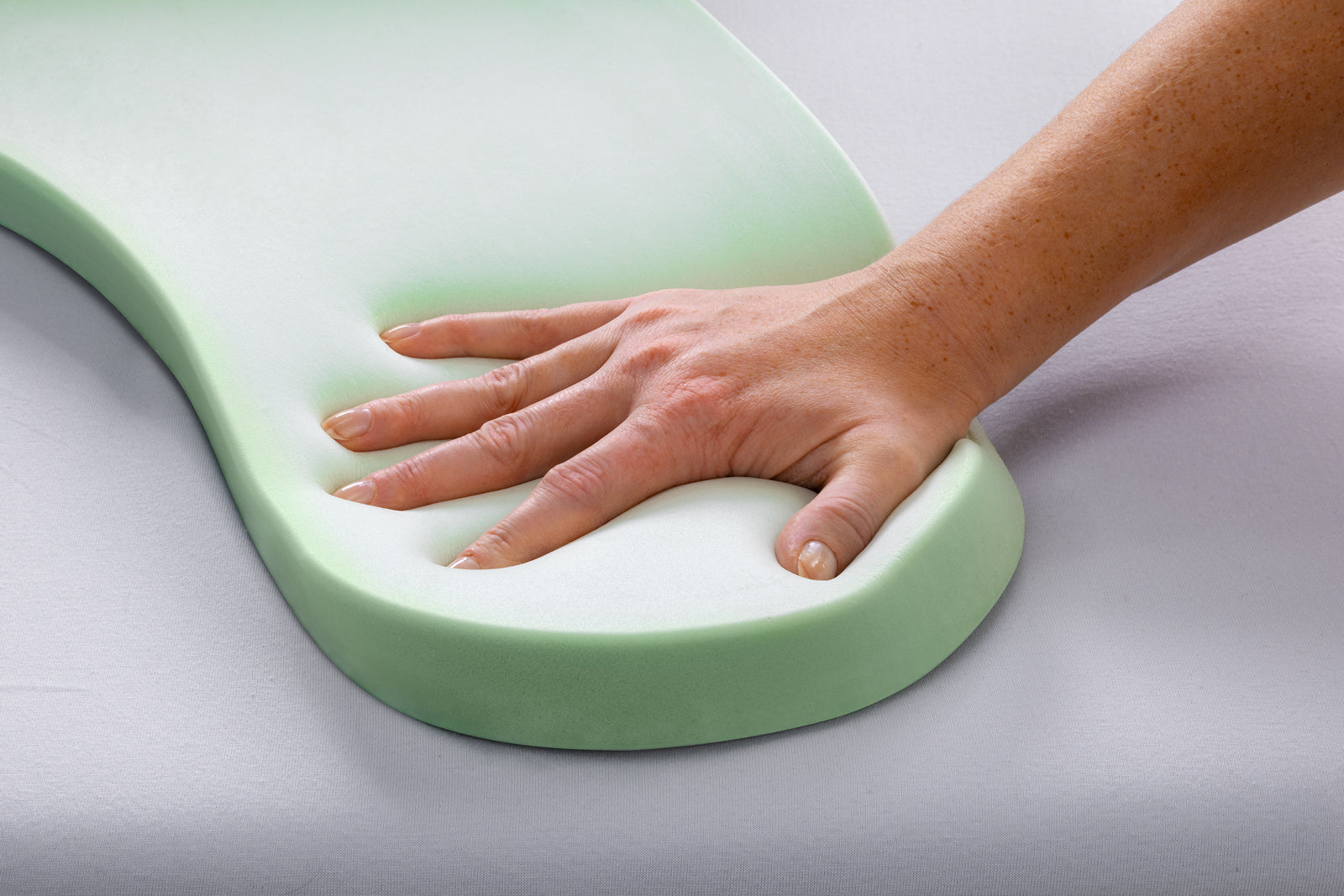 Hand drückt in den viscoelastischen Schaumkern eines REMILI Kissens